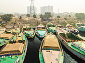 Aerial view of busy boats and cement industries along the Buriganga river with people working, Amin Bazar, Savar, Dhaka, Bangladesh.