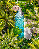 Aerial drone view of a swimming pool amidst palm trees on a resort on Gili Air island, Indonesia