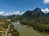 Luftaufnahme einer ruhigen und malerischen Landschaft mit einem Fluss, einem Berg und einem üppigen Wald unter einem wunderschönen Wolkenhimmel, Pak Ou District, Luang Prabang, Laos.