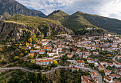 Luftaufnahme eines malerischen Dorfes in den Bergen mit charmanten Häusern und einer kurvenreichen Straße, Dhermi, Vlore, Albanien.