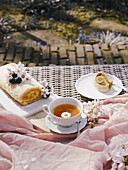A delicious Swiss roll filled with rich dulce de leche is presented on a garden table, accompanied by tea and spring flowers.