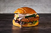 A delicious vegan gourmet burger with crispy courgettes, melted cheese, fresh salad and creamy sauce, served on a toasted bun. Perfect for food enthusiasts and burger lovers.