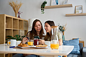 A lesbian couple enjoying a cosy breakfast at home, sharing a moment of connection and joy The image captures a sense of warmth, love and inclusivity