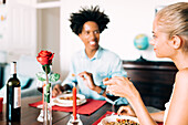 A romantic dinner scene with two people enjoying wine and a meal. A red rose and a candle create the right mood and emphasise the intimacy and warmth of the atmosphere.