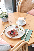A cosy coffee table with a plate of toast with fresh berries, a cup of coffee, syrup and whipped cream - perfect for a relaxed breakfast scene