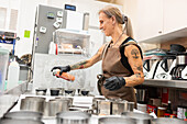 An experienced baker in an apron sprays moulds for the preparation of pastries in a professional kitchen The focus is on craftsmanship and the authentic Italian bakery atmosphere