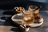 Cognac-based spice cocktails, garnished with cinnamon sticks and star anise, accompanied by almonds, peanuts and mixed nuts, presented on stylish ceramic crockery.