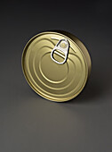 Close-up of a golden metal tin with a pull tab against a grey gradient background. This image captures the simplicity and industrial design of everyday packaging.