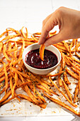 Crispy baked sweet potato sticks with spices, served with a spicy beet ketchup - perfect for a savoury and colourful snack experience