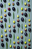 Aesthetic arrangement of green and black olives with leaves on a soft pastel background The minimalist pattern brings out the natural beauty and colour contrast of the elements