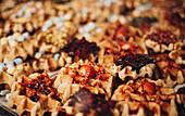 A tantalising display of waffles decorated with chocolate, strawberries and nuts in the window of a patisserie.