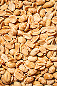 Top view of a close-up showing raw peanuts with a pronounced orange colour and a textured surface - ideal for making peanut butter.