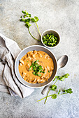 A delicious beef stroganoff dish with tender slices of meat in a creamy sauce, garnished with fresh coriander Perfectly presented with a separate bowl of chopped herbs