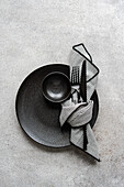 Elegant black and white placemat with black plate, bowl and cutlery and striped napkin. Perfect for modern, minimalist dining themes.