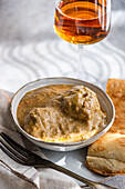 A traditional Georgian dish, satsivi, consists of succulent chicken in a rich walnut sauce, elegantly presented with bread and served with a glass of rare amber wine.
