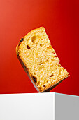 A delicious piece of panettone with a bright red background This traditional Christmas dessert is enriched with dried fruit and is perfect for Christmas parties and as a gift