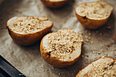 Halved pears, generously filled with dor bleu cheese and sprinkled with chopped nuts, are presented on a rustic surface, offering a blend of textures and flavours perfect for gourmet snacks or sophisticated starters.