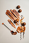 Chocolate balls on a cream-coloured surface. A decorative caramel swirl gives the balls a sweet touch and the scattered cocoa nibs make for a delightful sight.