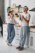 Two blind people enjoy coffee and laughter in a cosy kitchen. One of them is holding a white stick that symbolises inclusion and friendship. Bright, relaxed and warm atmosphere.