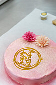 A pale pink birthday cake with pastel-coloured floral decorations on the top The cake is decorated with a happy birthday message and adds a special charm to special celebrations