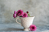 An enchanting floral arrangement with bright pink flowers in a textured vintage cup The soft, blurred background gives the image an elegant and delicate touch that is perfect for decoration