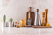 A selection of stylish kitchen utensils and plants set against a marble background, perfect for interior design themes.