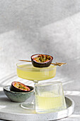 A lively cocktail of gin, tonic and passion fruit juice, garnished with a fresh passion fruit half. Served in a stylish glass on a minimalist concrete tray, ideal for modern entertaining or summer parties.