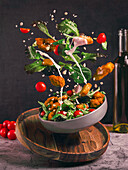 Dynamic composition showing a fresh salad with lettuce, cherry tomatoes and crunchy elements in the air, emphasised by flying croutons and dressing for a lively look