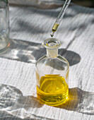 A pipette that dispenses oil into a small glass bottle. Perfect for illustrating topics relating to wellness, aromatherapy or natural products.