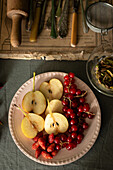 Sliced pears, redcurrants and strawberries lie on a vintage-style plate. Rustic utensils can be seen in the background, adding to the autumnal ambience.