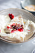 Traditionelle ukrainische varenyky, gefüllt mit Kirschen, elegant serviert mit cremiger saurer Sahne und gekrönt mit knackigen gehackten Nüssen für eine perfekte Geschmacksmischung.