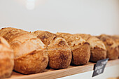 Rows of golden, crusty bread lie on a wooden shelf and embody the essence of a traditional bakery The aroma and warmth of freshly baked bread fills the room