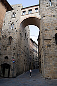 Medieval charm of Volterra, Tuscany This picture shows a narrow cobbled street flanked by old stone buildings with arched passageways, reflecting the town's rich history and timeless beauty