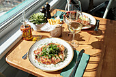 A cosy table set with gourmet snacks and glasses of wine The sunlight streaming through the window creates an inviting atmosphere.