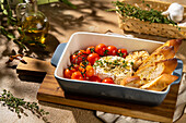 A freshly baked Camembert cheese with cherry tomatoes and crispy toasted bread, garnished with thyme. Perfect for a cosy meal or a starter, served in an elegant oven dish.