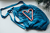 An eye-catching image of heart-shaped candy canes in a bright blue drawstring bag, strategically placed on a minimalist white background that brings a festive theme to the fore.
