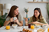 A loving lesbian couple having a cosy breakfast at home, surrounded by morning light and comfort Their expression of affection reflects pride and equality in the LGBTQIA+ community