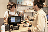 A welcoming café atmosphere with a barista helping a customer The interaction captures the exchange at the counter and emphasises customer service and hospitality