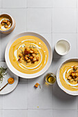 Savoury, creamy cauliflower curry soup, garnished with crispy croutons and rosemary Served on white tiles, it offers a homemade gourmet presentation with artisan flair