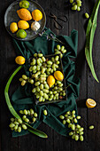 A vibrant presentation of green grapes, lemons and limes on a dark wood surface. The contrasting textures and colours create a fresh and natural composition.