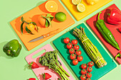 Fresh fruit and vegetables on colourful chopping boards. Oranges, limes, strawberries, cherry tomatoes and greens make for an eye-catching, healthy look.