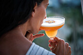 A woman enjoys a cocktail on a terrace as the sun sets, creating a relaxed and serene atmosphere. The perfect moment to relax and enjoy the view.