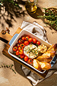 Savour the sight of baked camembert with cherry tomatoes, garlic and fresh herbs. The dish is rounded off with toasted baguette slices and offers a delicious culinary experience.