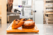 A close-up of freshly baked Italian biscuits on a wooden tray in a bakery The background blurs to emphasise the delicious treats and create an inviting atmosphere