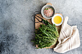 Fresh rocket, pink Himalayan salt and olive oil on a rustic wooden chopping board, with old scissors and a linen cloth for a natural kitchen aesthetic.