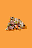 Delicious slice of pizza, flavoursomely topped with roast beef, truffle sauce, mozzarella, porcini mushrooms and fresh cherry tomatoes. Generously garnished with green onions on a bright orange background.