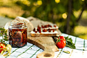 A rustic scene in which canapes are being prepared. Fresh tomatoes, a jar of pickled vegetables and slices of bread on a wooden board create a cosy culinary atmosphere.