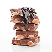 A tantalising stack of chocolate bars filled with almonds and covered in chocolate syrup. The rich texture and shiny surface make it irresistible. Perfect for dessert themes.