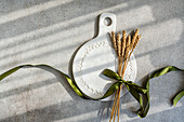A beautifully laid table with a round ceramic table and wheat stalks tied together with a ribbon creates an elegant, rustic ambience that is perfect for autumn gatherings