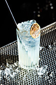 A refreshing gin and fizz cocktail, served in a tall glass, garnished with a slice of lime and filled with ice cubes
